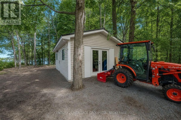 Small building with double doors and tractor next to trees - 1127 Perry Lane Frontenac