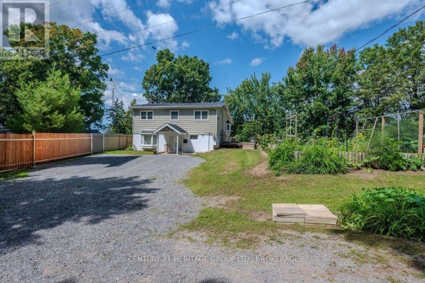 House with gravel driveway, wooden fence, and garden - 1127 Perry Lane Frontenac