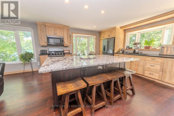 Kitchen with granite island, wooden cabinets, and stainless steel appliances - 1127 Perry Lane Frontenac
