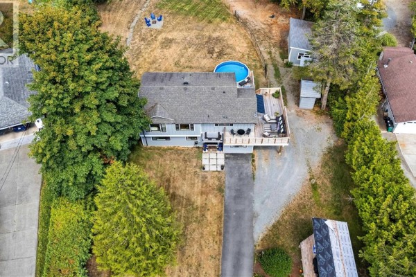 Aerial view of a grey two-story house with a deck, swimming pool, and surrounding trees. - 1127 Stuart Cres, Cobble Hill