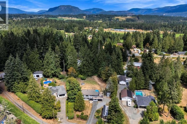 Aerial view of houses and trees in a rural neighborhood with distant mountains. - 1127 Stuart Cres, Cobble Hill