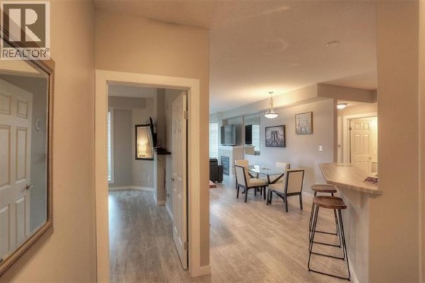 Hallway view into a living and dining area with a kitchen island. - 1128 Sunset Drive Unit# 706 Lot# 52, Kelowna