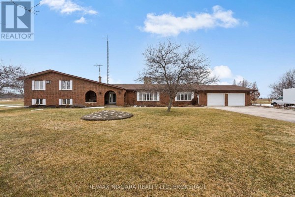 Close-up of the front entrance featuring brick and stone details with a porch. - 11292 Golf Course Road, Wainfleet