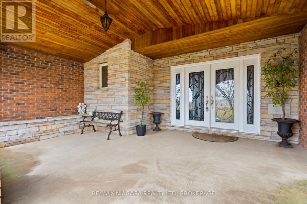 Side view of the house with driveway, car, and landscaped yard. - 11292 Golf Course Road, Wainfleet