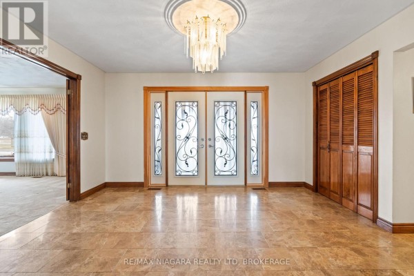 Covered porch with stone accents, decorative lighting, and seating area. - 11292 Golf Course Road, Wainfleet