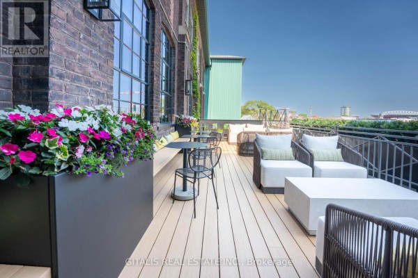 Outdoor patio area with lounge seating, tables, and floral planters. - 112c - 219 Dufferin Street, Toronto