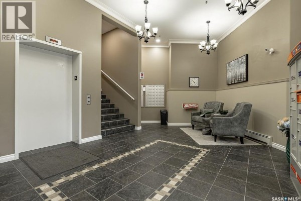 Apartment building lobby with elevator, stairs, seating area, and mailboxes. - 113 106 Armistice Way, Saskatoon