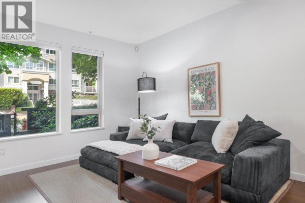 Living room with a charcoal sectional sofa, coffee table, and windows. - 113 119 W 22nd Street, North Vancouver