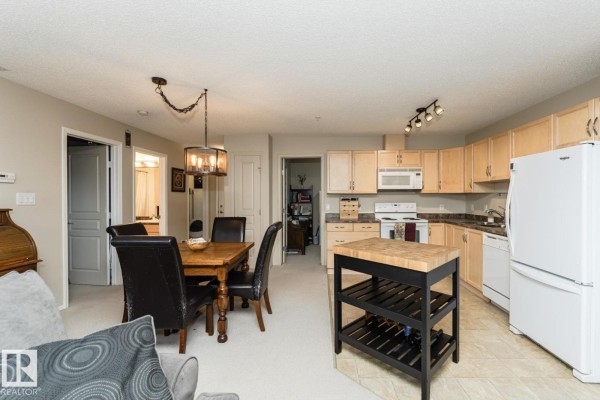 Outdoor community area with a gazebo, seating, and green lawn. - #113 16035 132 St Nw, Edmonton