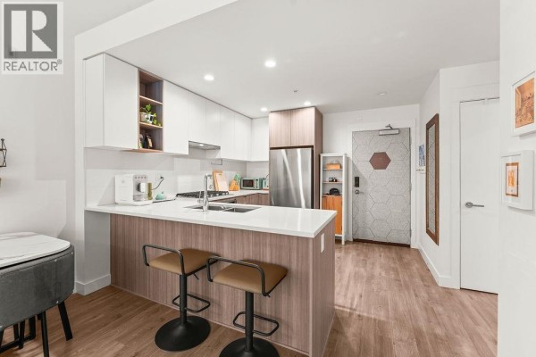 L-shaped kitchen with breakfast bar seating and a view of the entryway. - 113 750 Dogwood Street, Coquitlam