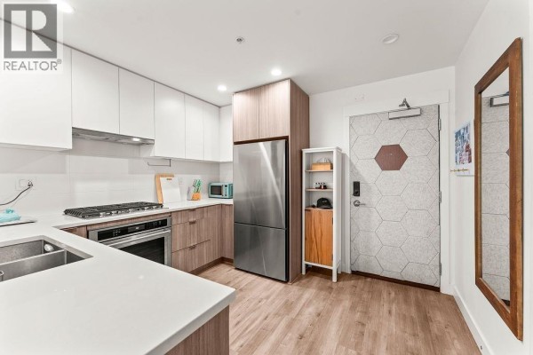 Corner kitchen view showing stainless steel refrigerator and honeycomb patterned front door. - 113 750 Dogwood Street, Coquitlam