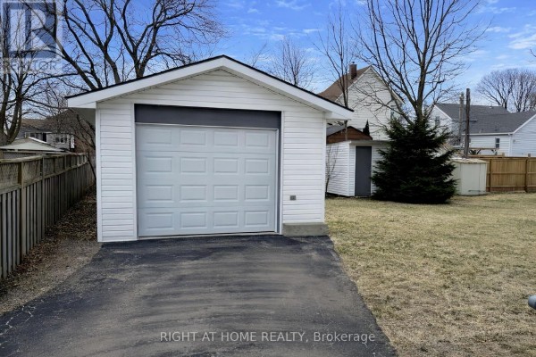 Detached single-car garage with white siding and a paved driveway - 113 Anglesea Street, Goderich)