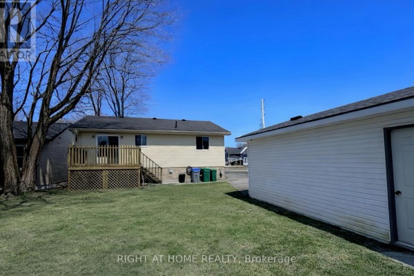 View of the backyard with grass, deck, and detached garage - 113 Anglesea Street, Goderich)