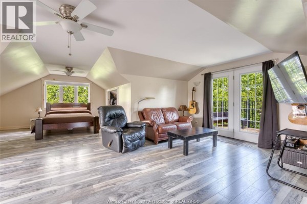 Bedroom with king bed, leather furniture, TV, and balcony access - 113 Beach Court Stoney Point