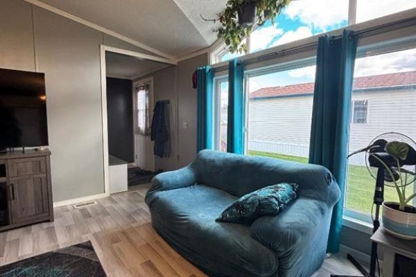 Living room with a large window, teal curtains, and a view of the exterior. - 113 Clark Crescent, Rural Grande Prairie No  1, County Of