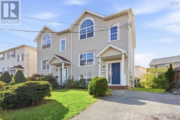 Exterior view of a light beige duplex with blue front doors and green lawn. - 113 Feruz Crescent, Halifax