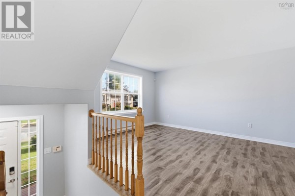 View from a hallway looking into a living room with wood-look flooring and large window. - 113 Feruz Crescent, Halifax