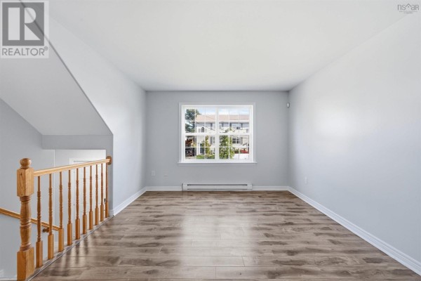 Living room with light blue walls, wood-look flooring, and a window overlooking houses. - 113 Feruz Crescent, Halifax