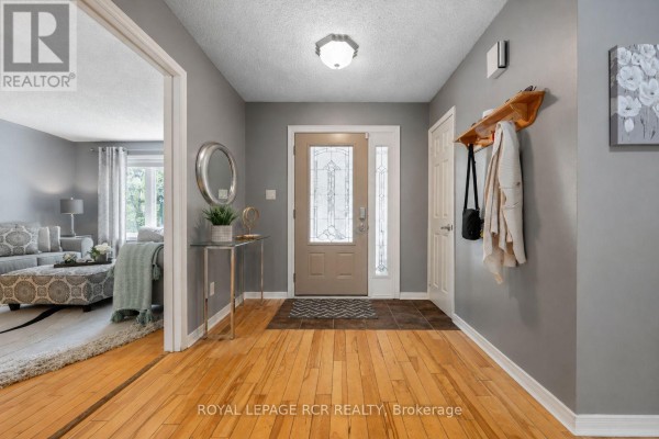 Interior foyer with hardwood floors, grey walls, coat rack, and a view into the living room. - 113 Meadow Drive, Orangeville