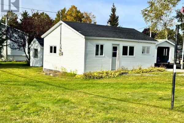 Side view of a white vinyl-sided house with a black roof and multiple windows, set on a green lawn. - 113 Midland Row, Pasadena