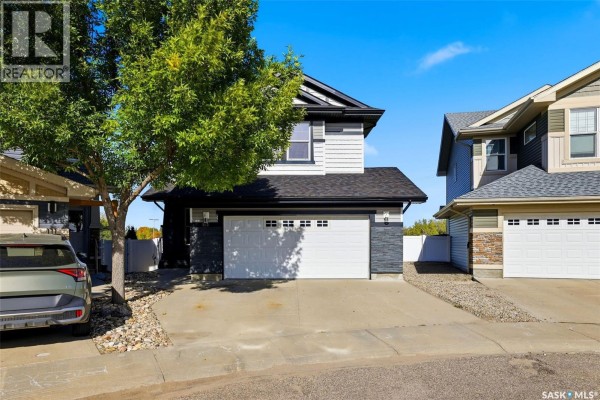 Exterior of a two-story home with a double car garage, driveway, and adjacent properties. - 113 Poplar Bluff Crescent, Regina