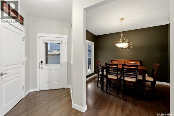 Entryway of a home with hardwood floors, a white door, and an adjacent dining room. - 113 Poplar Bluff Crescent, Regina