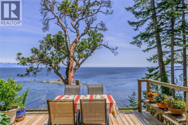 Outdoor dining table and chairs on wooden deck with ocean view. - 1130 Berry Point Rd, Gabriola Island