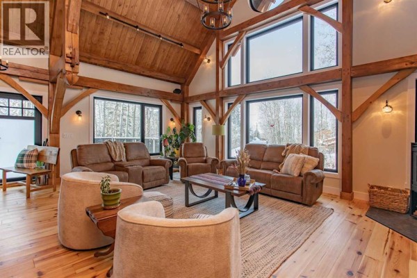 Living room with vaulted timber ceiling, stone fireplace, large windows, and leather furniture. - 1130 Breakers Way, Sunbreaker Cove