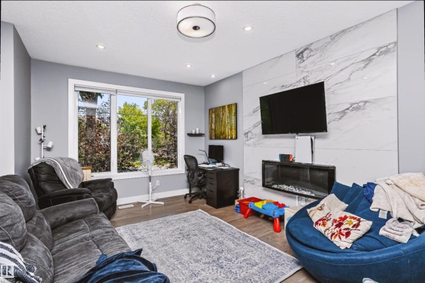 Living room with grey walls, beanbag chair, sofa, fireplace, and television. - 11305 79 Av Nw, Edmonton