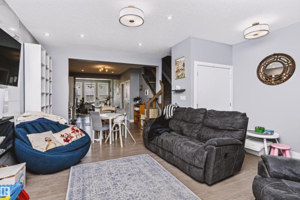 Living room looking towards dining area and kitchen, with sectional sofa and fireplace. - 11305 79 Av Nw, Edmonton