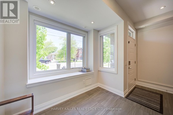 Interior entrance area with large windows overlooking the street, tiled floor, and white trim. - 1130a Islington Avenue, Toronto