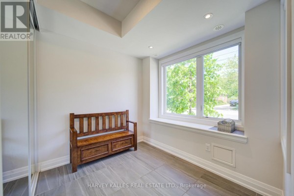 Entrance area with a wooden bench, large window with a wide sill, and tiled floor. - 1130a Islington Avenue, Toronto
