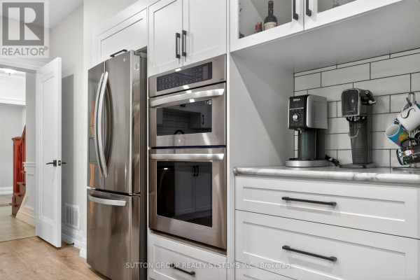 Modern kitchen with white cabinets, subway tile backsplash, large island, and stainless steel appliances. - 11310 Taylor Court, Milton