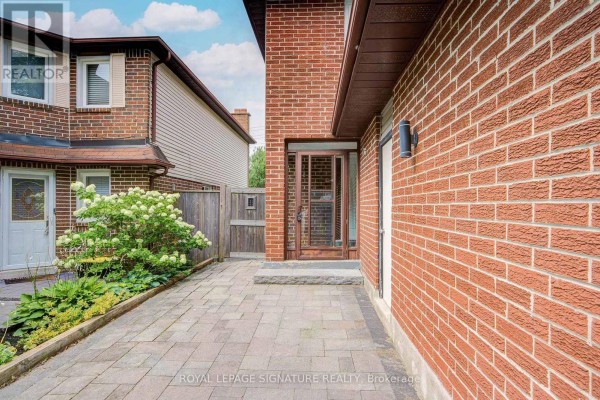 Side view of the house showing a paved walkway, brick exterior, and front entrance. - 1132 Cedarcroft Crescent, Pickering