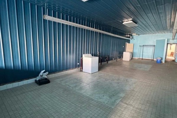 Interior room with blue corrugated metal walls, tiled floor, and two washing machines. - 1132 Fifth Street, Estevan