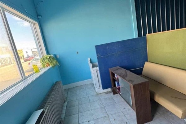 Corner of a room with a large window, radiator, and furniture including a sofa. - 1132 Fifth Street, Estevan