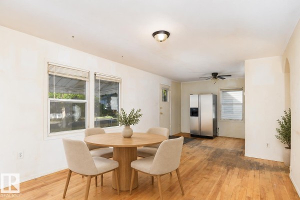 Virtual staged dining area with a round table, four chairs, and hardwood floors. - 11321 89 St Nw, Edmonton