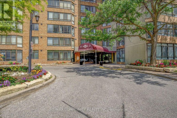 Entrance of the apartment building with a red awning over the doors. - 1133 - 25 Bamburgh Circle, Toronto