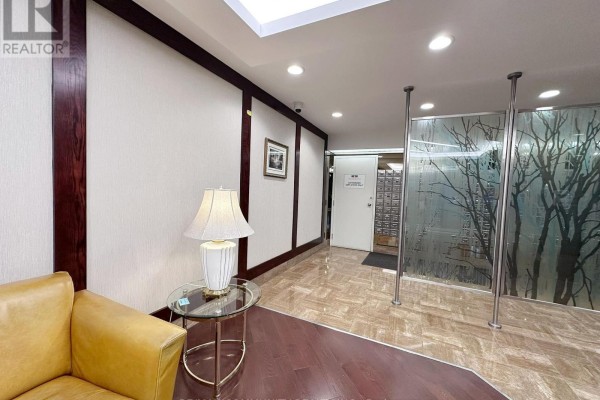 Apartment building hallway with wood paneling, marble floors, and frosted glass partitions. - 1133 - 25 Bamburgh Circle, Toronto