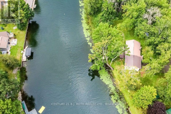 Overhead aerial view of a house on a narrow river, showing the water, green trees, and vegetation. - 1133 Severn River Road, Gravenhurst