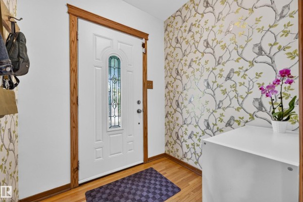 Interior entryway with a white door, wooden trim, and bird-themed wallpaper. - 11346 69 St Nw, Edmonton