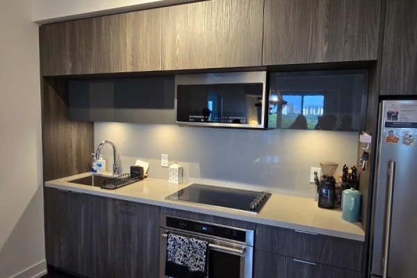 Compact kitchen with grey wood cabinets, stainless steel appliances, and induction stovetop. - 1136 - 25 Adra Grado Way, Toronto