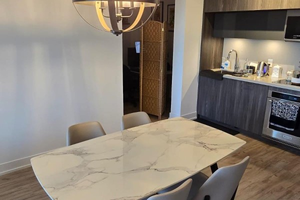 Dining area with a white marble-patterned table and four upholstered chairs next to kitchen. - 1136 - 25 Adra Grado Way, Toronto