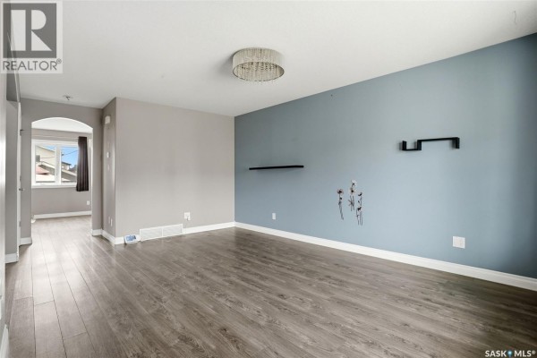 Living room with two-tone walls, wood-look flooring, and doorway to another room. - 1137 Jurasin Street N, Regina