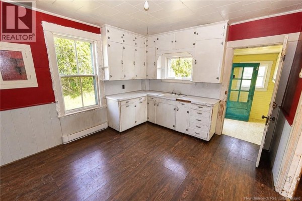 Kitchen with white cabinets, white countertop, double sink, and red and white paneled walls. - 1137 Route 776, Grand Manan