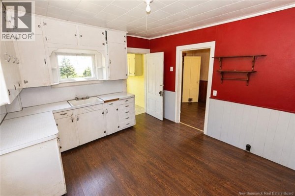 View of a kitchen with white cabinets, white countertop, double sink, and doorways to other rooms. - 1137 Route 776, Grand Manan