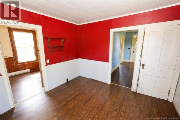 Interior view of a room with red and white paneled walls, wooden floor, and doorways to other rooms. - 1137 Route 776, Grand Manan