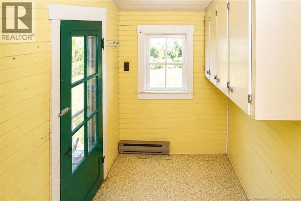 Small yellow room with a green glass door, white cabinets, and a window overlooking greenery. - 1137 Route 776, Grand Manan