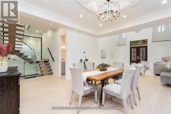 Modern dining room with velvet chairs, wooden table, and glass staircase - 1138 Garden Road Mississauga
