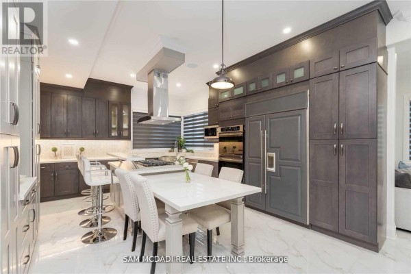 Modern kitchen with island, bar stools, and integrated appliances - 1138 Garden Road Mississauga